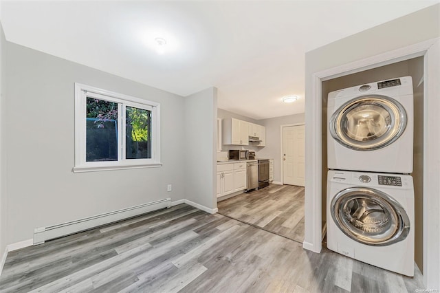 washroom featuring light hardwood / wood-style flooring, baseboard heating, and stacked washer and clothes dryer