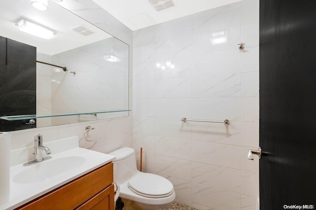 bathroom with vanity, toilet, and tile walls