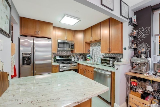 kitchen with decorative backsplash, stainless steel appliances, light stone countertops, and sink