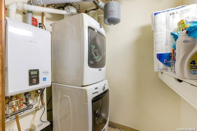 laundry area with stacked washer / drying machine and water heater