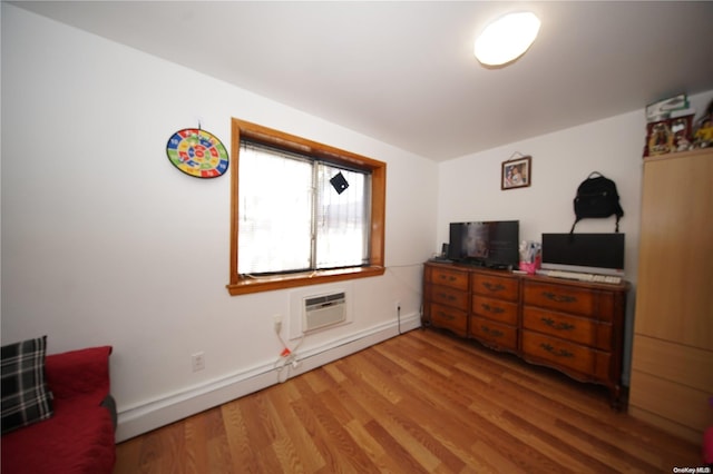 bedroom featuring an AC wall unit, hardwood / wood-style floors, and a baseboard radiator