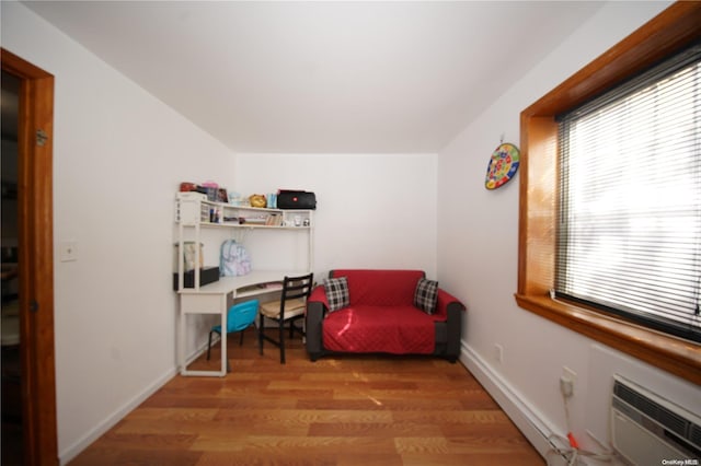 sitting room featuring a wall mounted air conditioner and hardwood / wood-style flooring