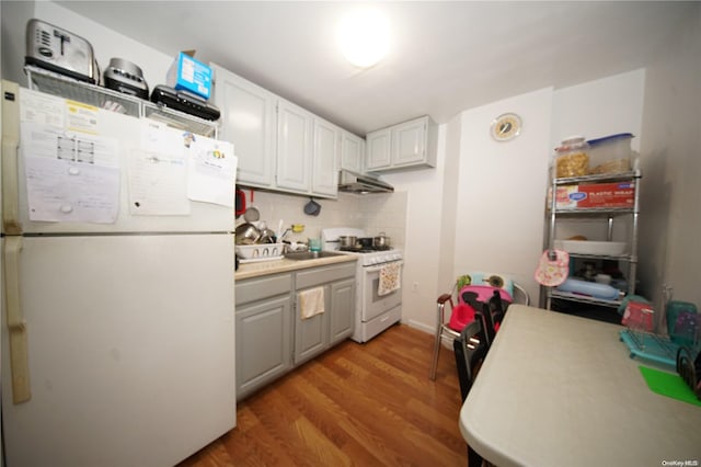 kitchen featuring white cabinetry, sink, white appliances, decorative backsplash, and hardwood / wood-style flooring