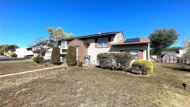 bi-level home with a front lawn and solar panels