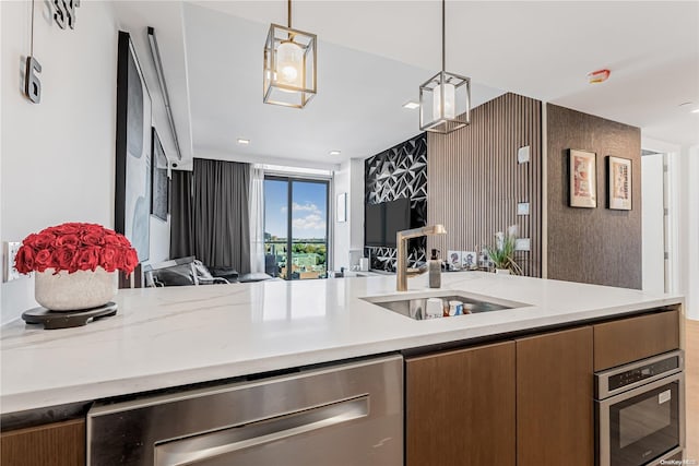 kitchen featuring decorative light fixtures, light stone counters, sink, and appliances with stainless steel finishes