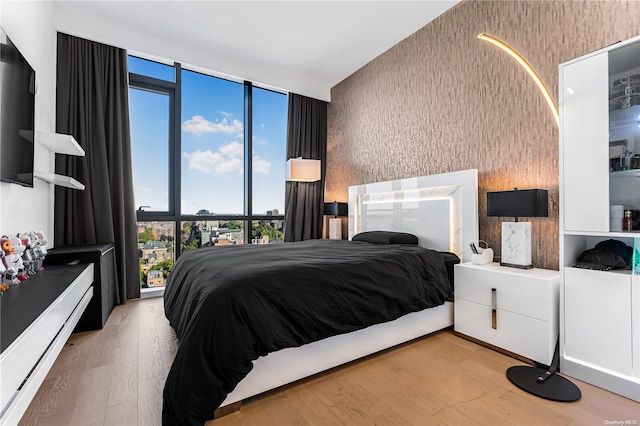 bedroom featuring a wall of windows and light wood-type flooring