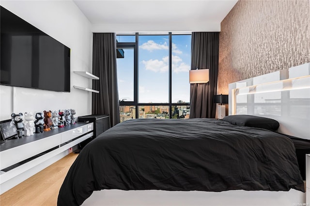 bedroom with expansive windows, hardwood / wood-style flooring, and multiple windows