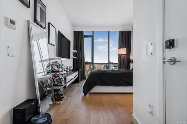 bedroom with hardwood / wood-style floors and a wall of windows