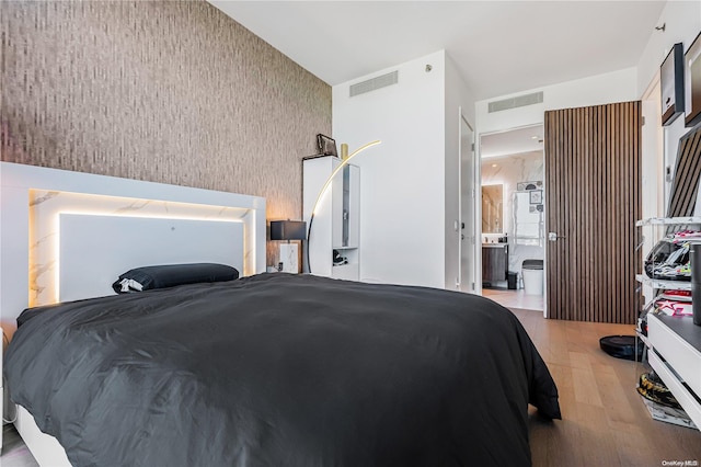 bedroom with light hardwood / wood-style floors and ensuite bathroom