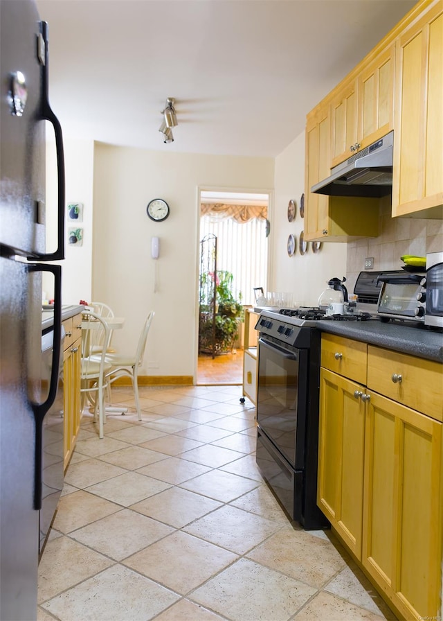 kitchen with backsplash, stainless steel refrigerator, and black range