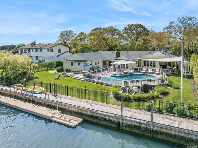 rear view of property featuring a yard, a water view, a patio, and a fenced in pool