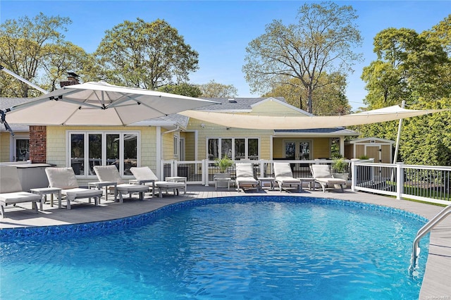 rear view of house with french doors, a patio, a fenced in pool, and a storage unit