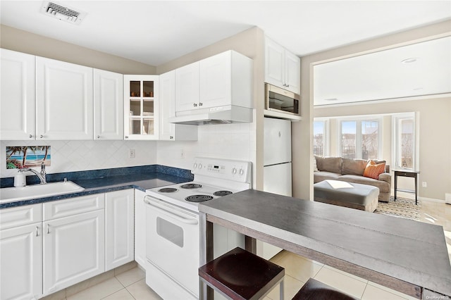 kitchen featuring white appliances, backsplash, white cabinets, sink, and light tile patterned floors