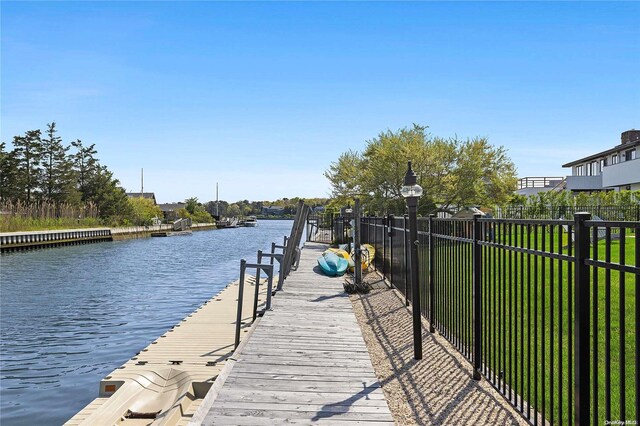 view of dock with a lawn and a water view