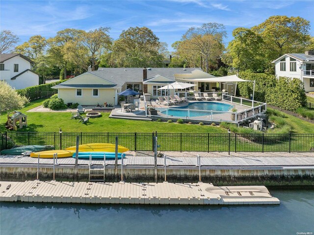 rear view of house featuring a water view, a yard, a fenced in pool, and a patio