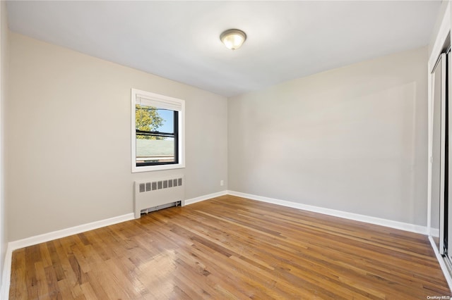 empty room featuring radiator and hardwood / wood-style floors