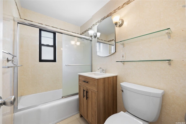 full bathroom with bath / shower combo with glass door, vanity, tile walls, tile patterned flooring, and toilet