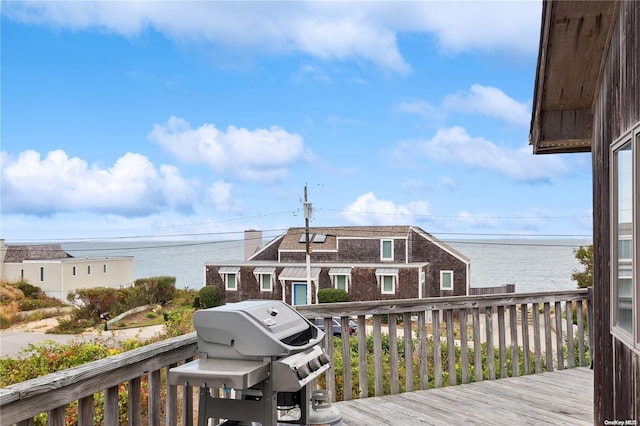 wooden terrace featuring area for grilling and a water view