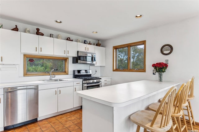 kitchen with kitchen peninsula, white cabinetry, sink, and stainless steel appliances