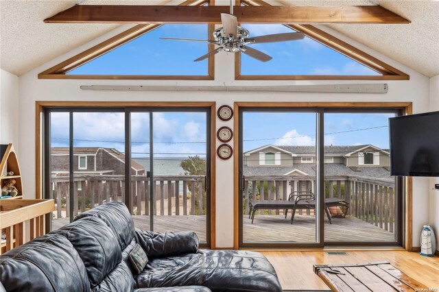 living room featuring beamed ceiling, hardwood / wood-style flooring, a wealth of natural light, and ceiling fan