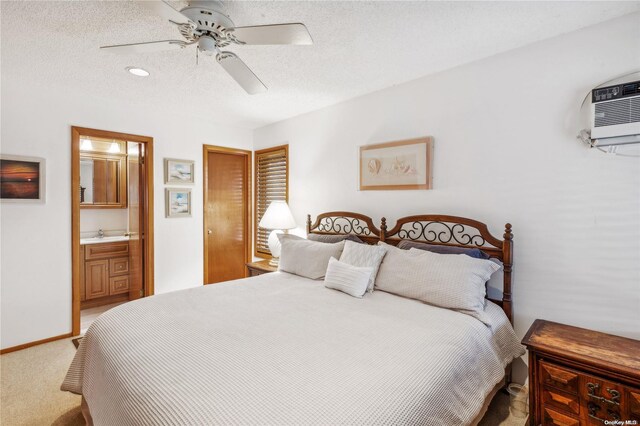 bedroom featuring a wall mounted air conditioner, ensuite bath, a textured ceiling, ceiling fan, and carpet floors