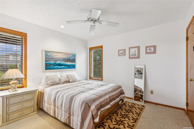 bedroom with ceiling fan, light carpet, and a textured ceiling