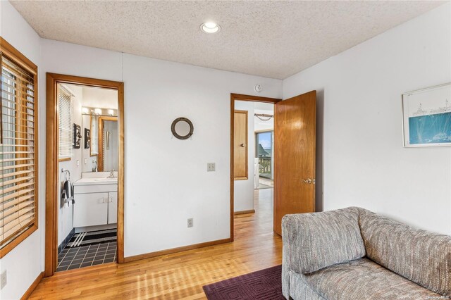 living room with a textured ceiling, light hardwood / wood-style flooring, and sink