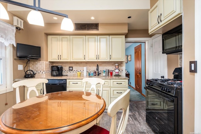 kitchen featuring cream cabinets, black appliances, hanging light fixtures, decorative backsplash, and light stone counters