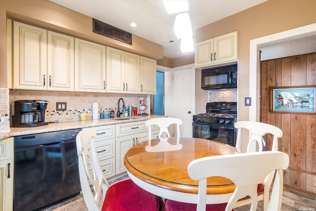 kitchen with decorative backsplash, sink, light hardwood / wood-style floors, and black appliances