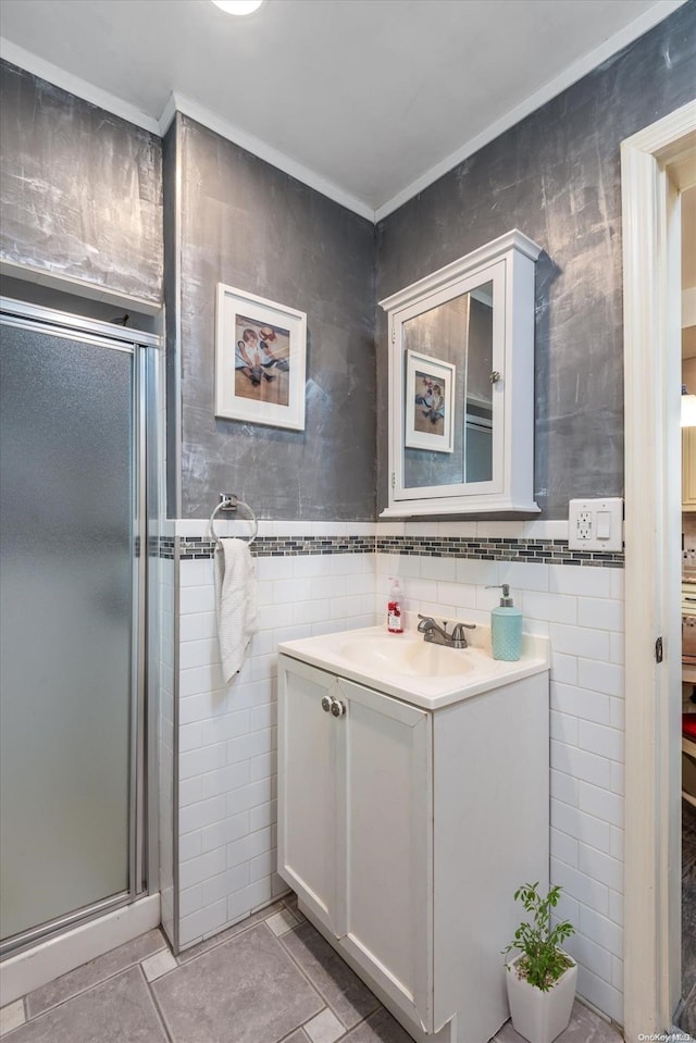 bathroom featuring tile patterned flooring, vanity, a shower with door, and tile walls