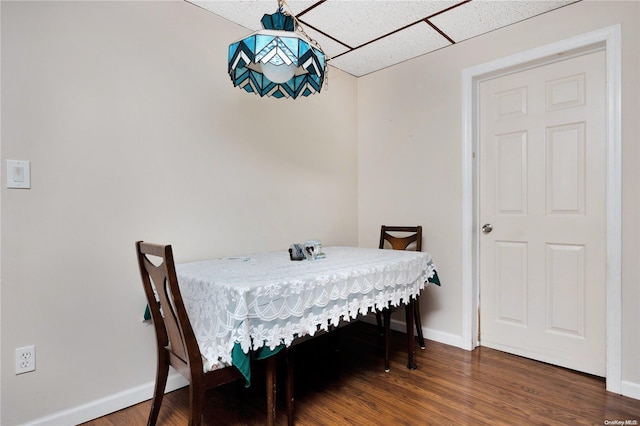 dining area with a paneled ceiling and dark hardwood / wood-style flooring