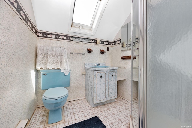 bathroom featuring toilet, vanity, tile patterned flooring, and lofted ceiling with skylight