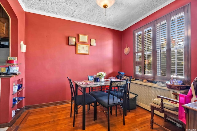 dining room featuring crown molding, a textured ceiling, and hardwood / wood-style flooring