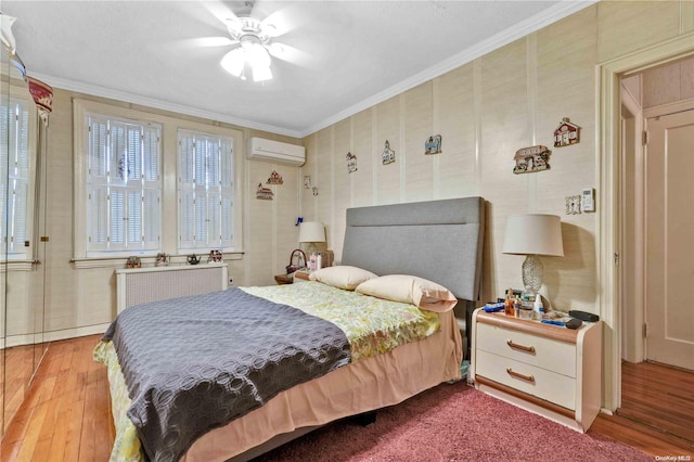 bedroom featuring ceiling fan, radiator heating unit, a wall mounted AC, wood-type flooring, and ornamental molding