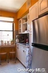 kitchen featuring white cabinets and stainless steel refrigerator