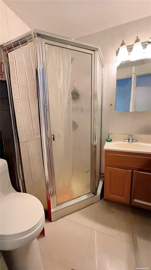 bathroom with tile patterned flooring, vanity, an enclosed shower, and toilet