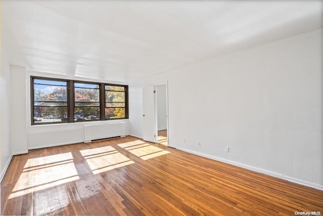 unfurnished room featuring radiator and light hardwood / wood-style flooring