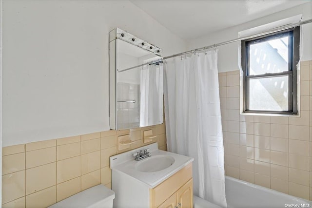 full bathroom with shower / bathtub combination with curtain, vanity, tile walls, and toilet