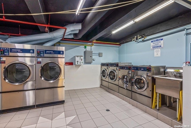 laundry room featuring washer and clothes dryer, tile patterned flooring, sink, and electric panel