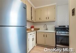 kitchen with appliances with stainless steel finishes, light wood-type flooring, cream cabinets, and sink