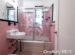 bathroom with a wealth of natural light, sink, tile walls, and enclosed tub / shower combo