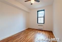 unfurnished room featuring ceiling fan, wood-type flooring, and radiator