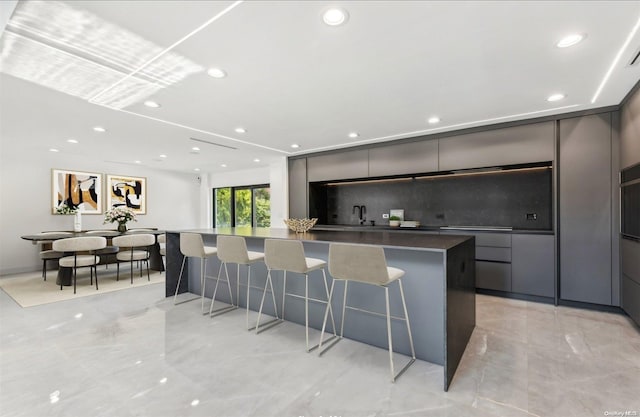 kitchen with sink, a kitchen breakfast bar, a spacious island, and backsplash