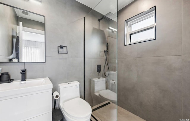 bathroom with a tile shower, vanity, and toilet