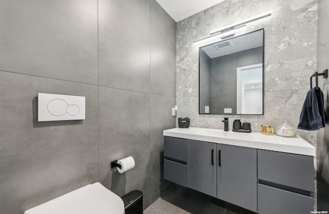 bathroom with tile patterned floors, vanity, toilet, and tile walls