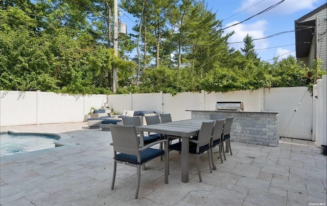 view of patio featuring a fenced in pool, an outdoor bar, and grilling area