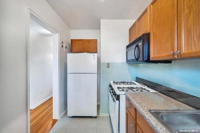 kitchen featuring light hardwood / wood-style flooring, white appliances, and sink