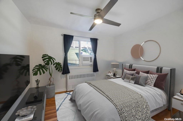 bedroom featuring ceiling fan, radiator heating unit, and light wood-type flooring