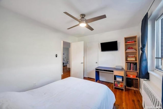 bedroom with radiator heating unit, dark hardwood / wood-style flooring, and ceiling fan