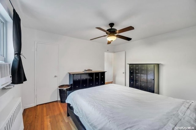 bedroom with hardwood / wood-style floors, radiator, and ceiling fan